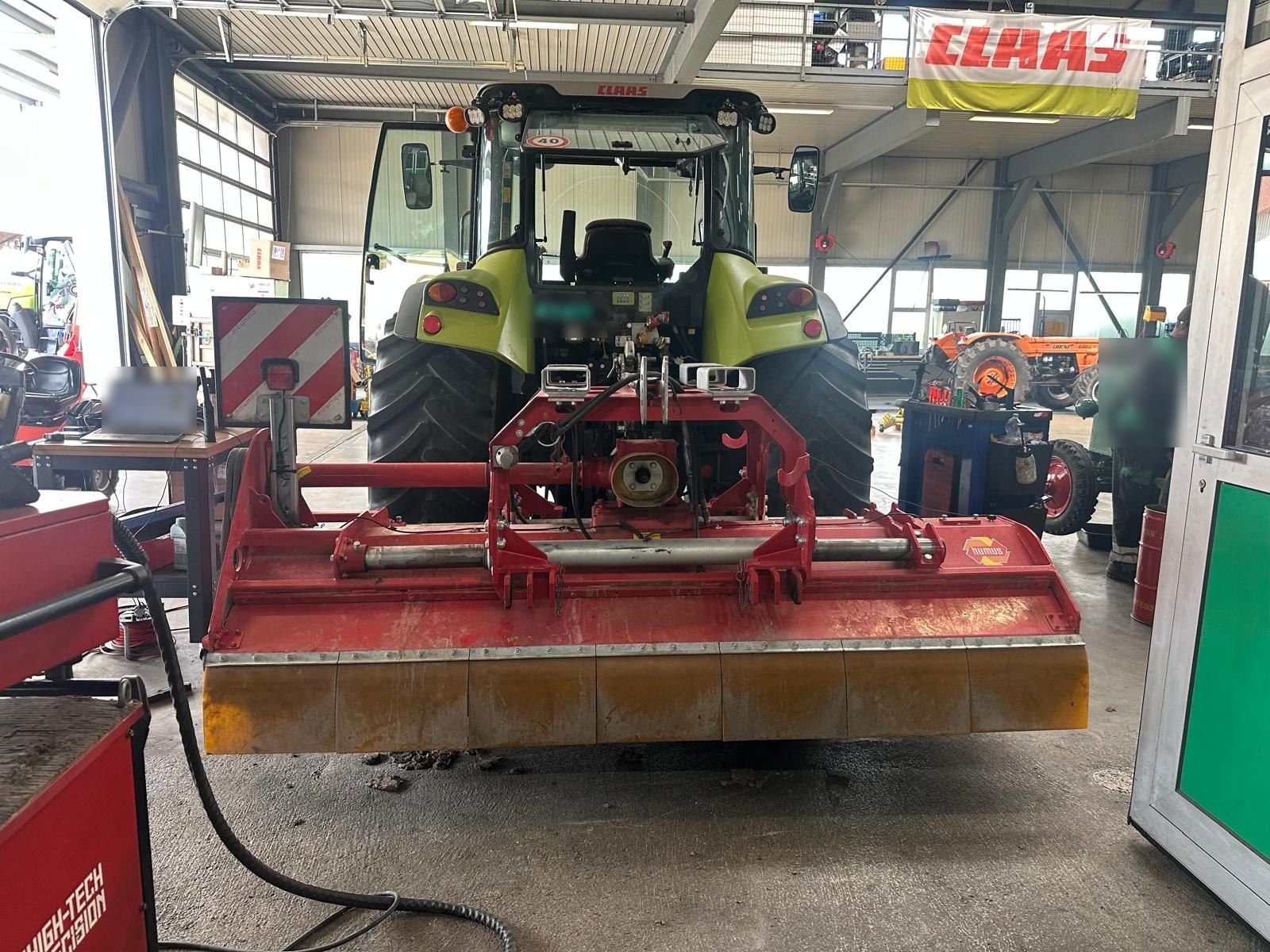 Broyeur à fléaux monté sur un tracteur dans un atelier de ferme, prêt pour l'équilibrage